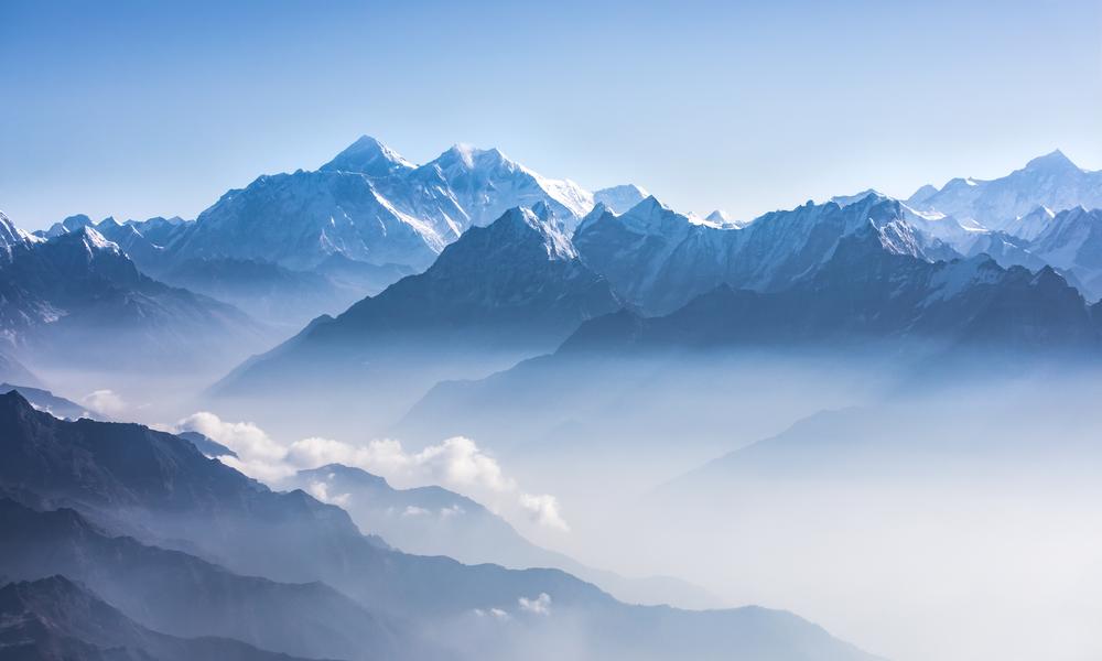 Daylight views of Mount Everest, Lhotse and Nuptse, and the rest of the Himalayan range from the air. Sagarmatha National Park, Khumbu valley, Nepal. The photo shows the soft white clouds and the light blue sky.