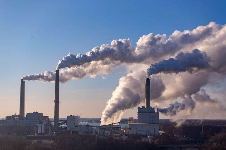 Black and grey smoke from coal fired power plant chimneys blowing across the sky.