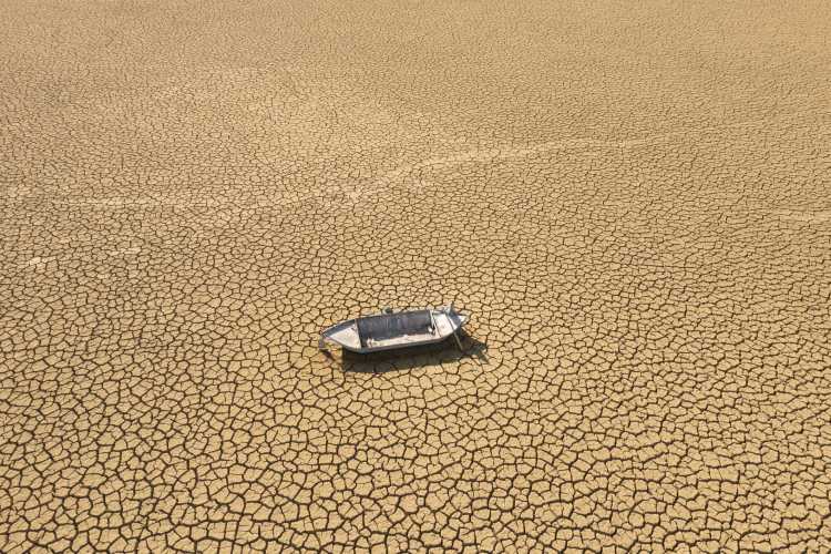 Aerial view of a single fishing boat on the dry surface of a drought lake bed. Burdur, Turkey.