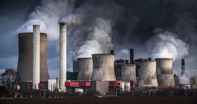 Chimneys and cooling towers from a coal fired power station releasing smoke and steam into the atmosphere.