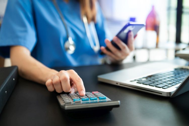 A woman in blue shirt used a calculator, smartphone, and tablet for medical costs at hospital.