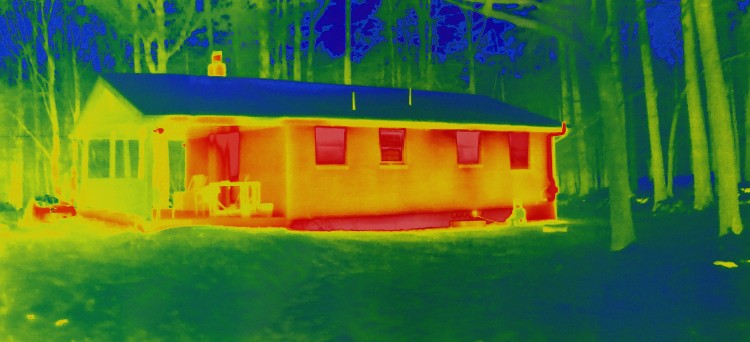 Bad insulation along with the roof in dark green and the foundation. House exterior, taken with infrared camera, shows more heat emission in the brighter areas ( light yellow and red).