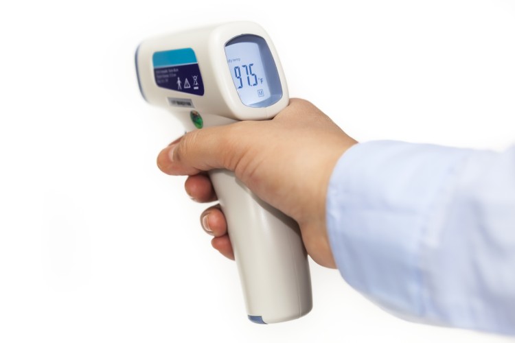 Woman hand held a white infrared medical thermometer with laser, showed 97.5 F.