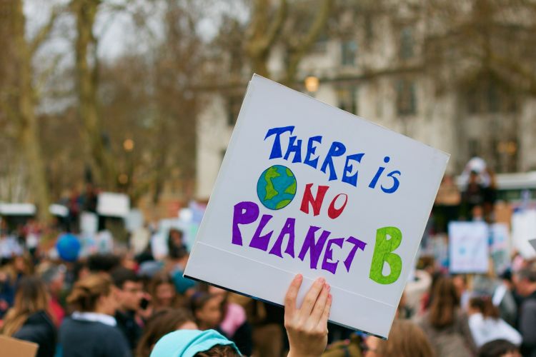 People marched for climate change. A woman's hand holds a sign that reads, 'There is no Planet B.'